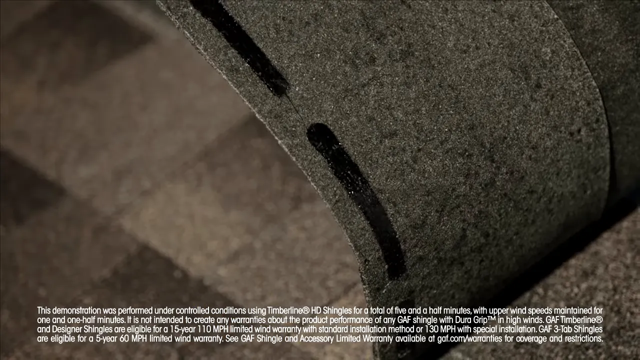 Close-up of the DuraGrip adhesive strip on a shingle tab—the bond that resisted uplift in the test.
